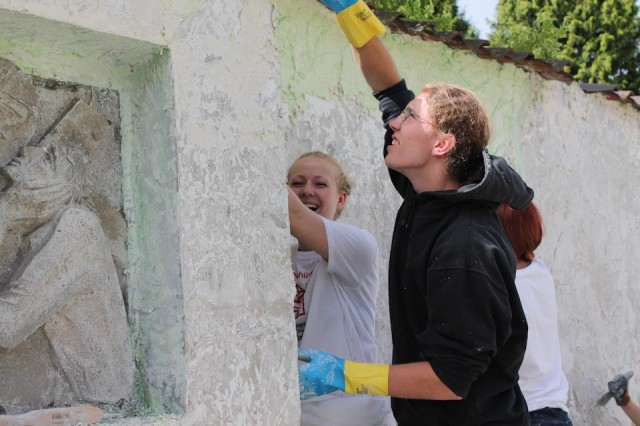 Engagiert beizt die Jugendbauhütte die alte Farbe von der Mauer ab