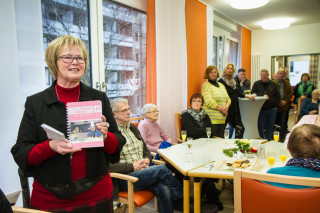 Mathilde Grewing hält einen Rückblick auf die 20-jährige Geschichte der Tagespflege - und präsentiert ein Kochbuch mit alten Rezepten, das Mitarbeiterinnen und Bewohner gemeinsam erstellt haben. Foto: SMMP/Bock