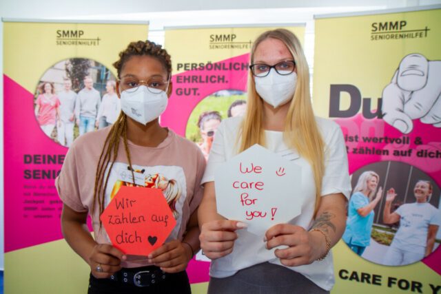 Die Auszubildenden Pamela Mudiwa Muringai und Meike Müller senden eione Botschaft: "We care for you!" Foto: SMMP/Ulrich Bock